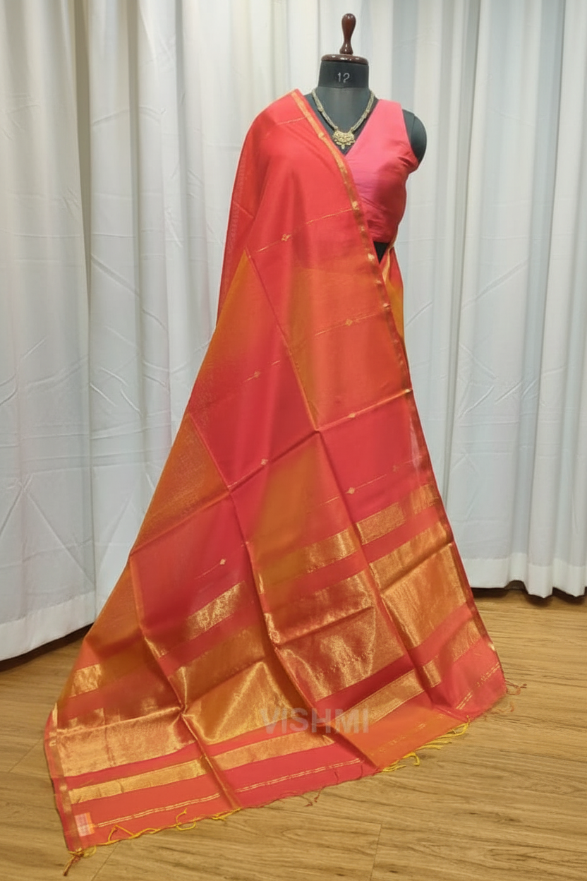 Red and orange saree with gold border on a wooden floor