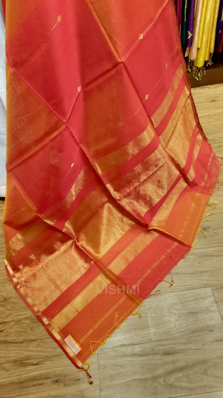 Red and orange saree with gold stripes on a wooden floor