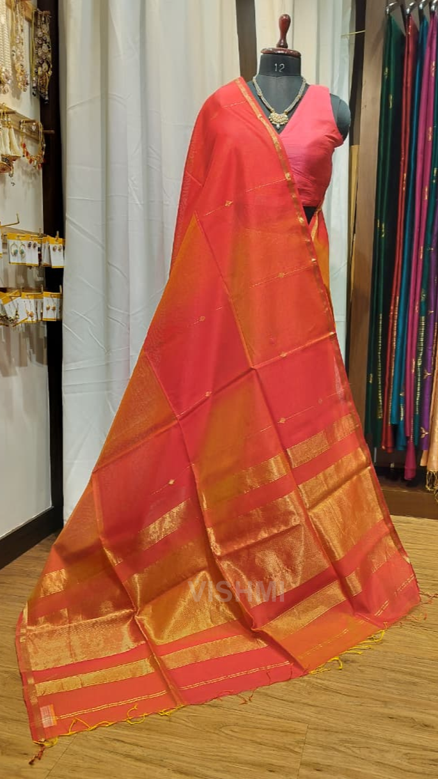 Red and orange saree with gold border on a wooden floor