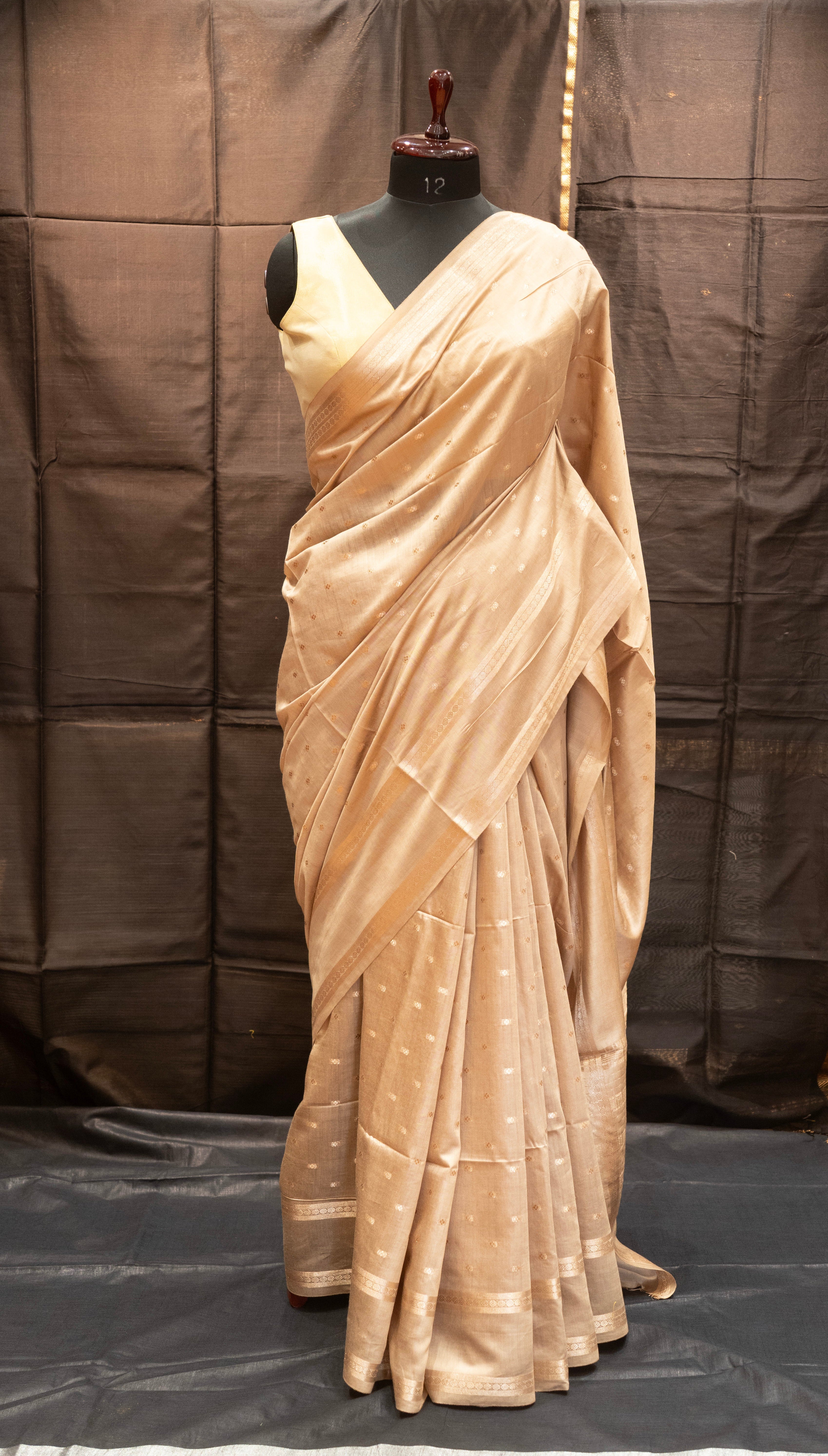 Beige saree on a mannequin against a plain background