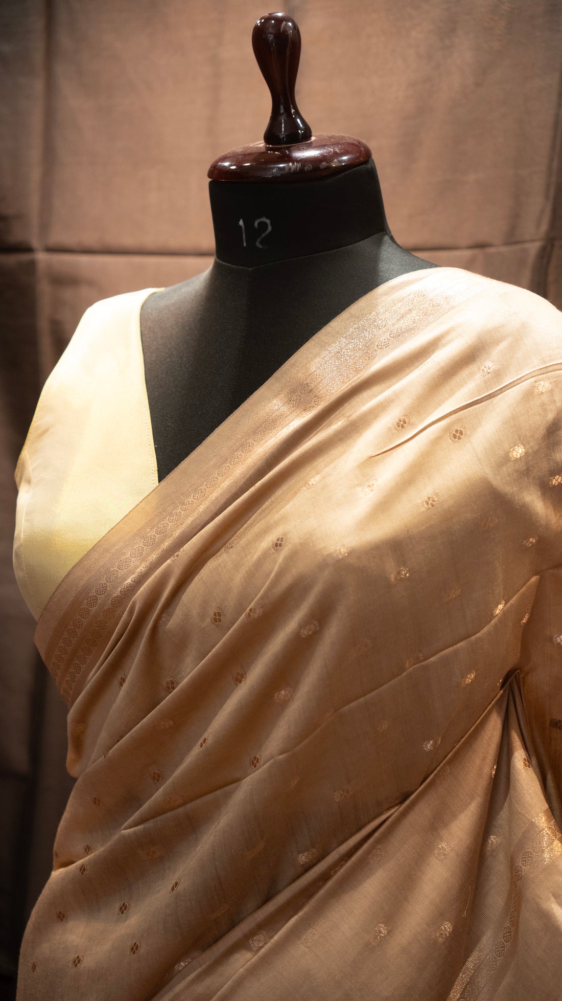 Beige saree on a mannequin against a plain background