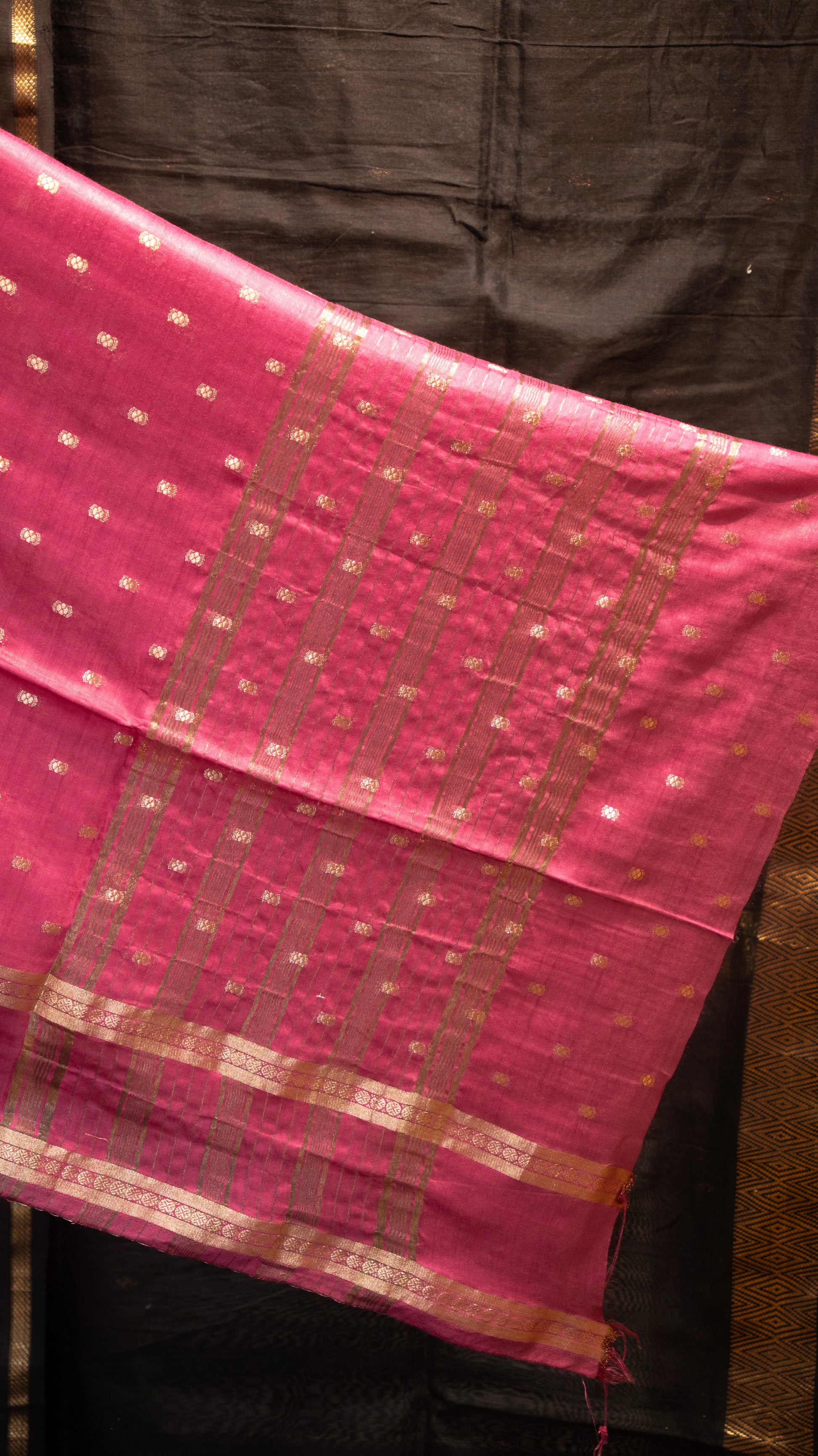 Pink fabric with a checkered pattern draped over a person wearing dark clothing.