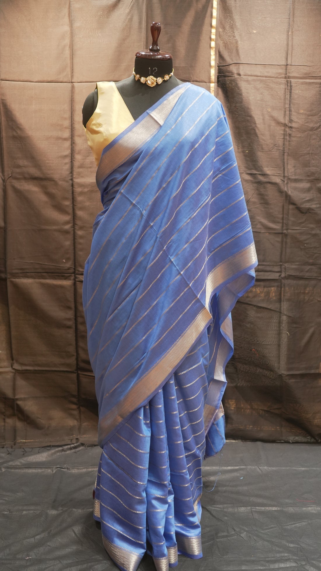 Blue striped fabric on a mannequin against a brown background