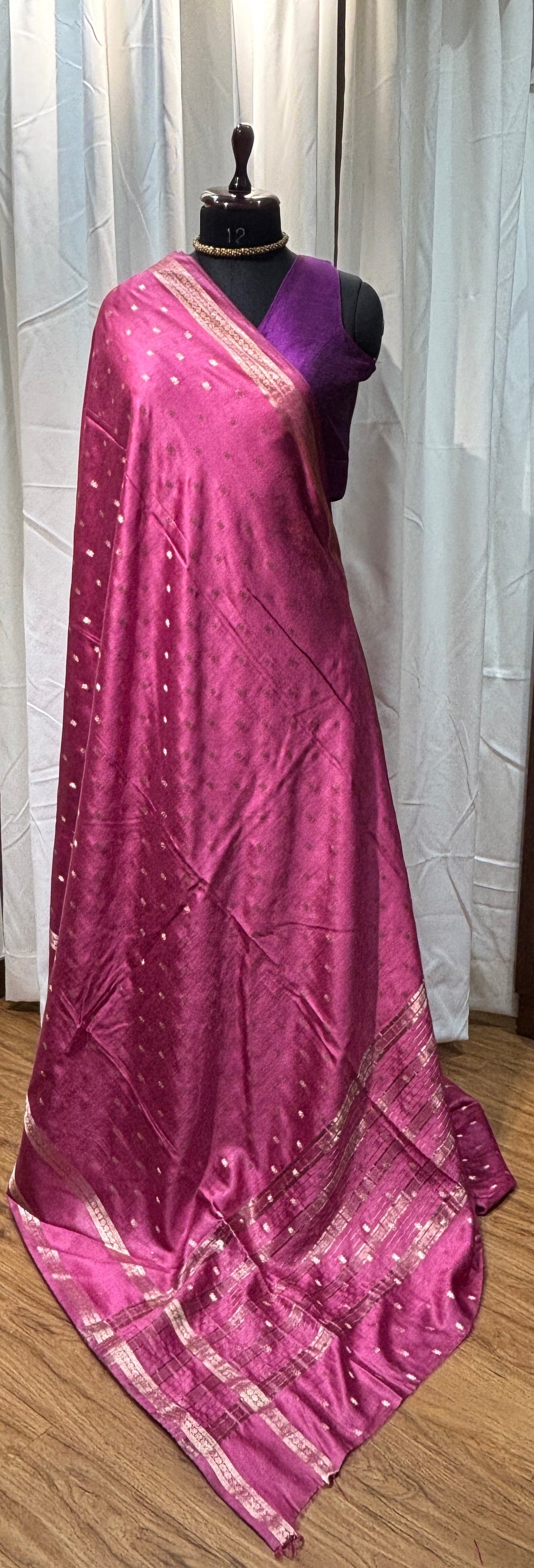 Purple saree with silver border on a mannequin against a wooden floor background