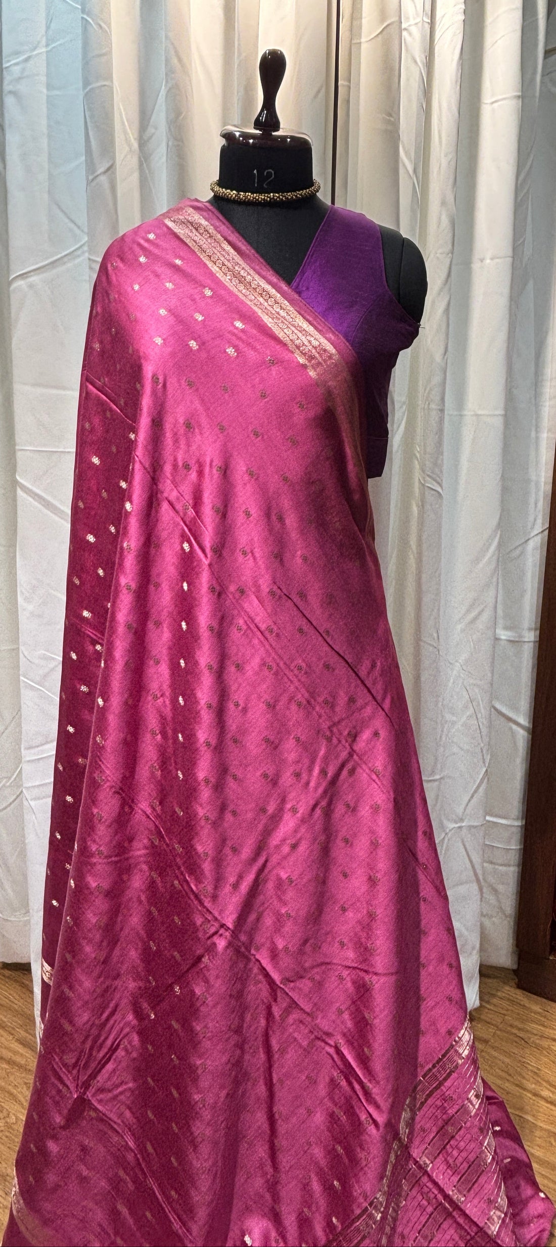 Purple saree with silver border on a mannequin against a wooden floor background