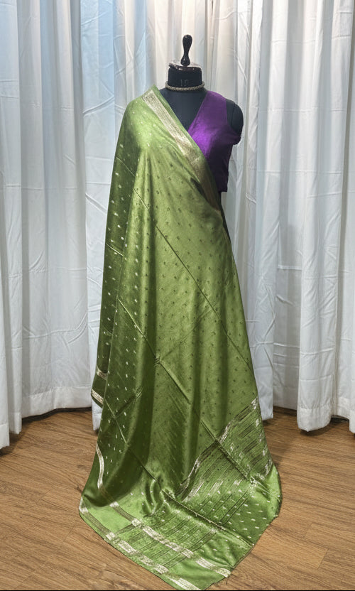 Green fabric on a wooden floor with colorful fabric in the background