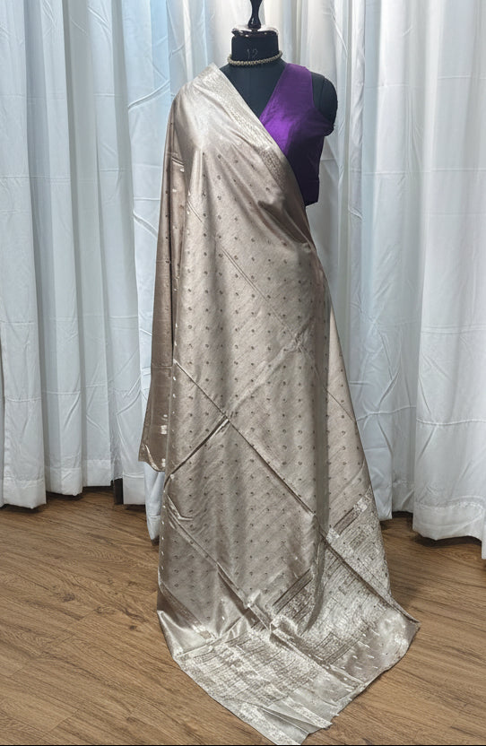 Mannequin wearing a long, light-colored dress with a pattern on a wooden floor.