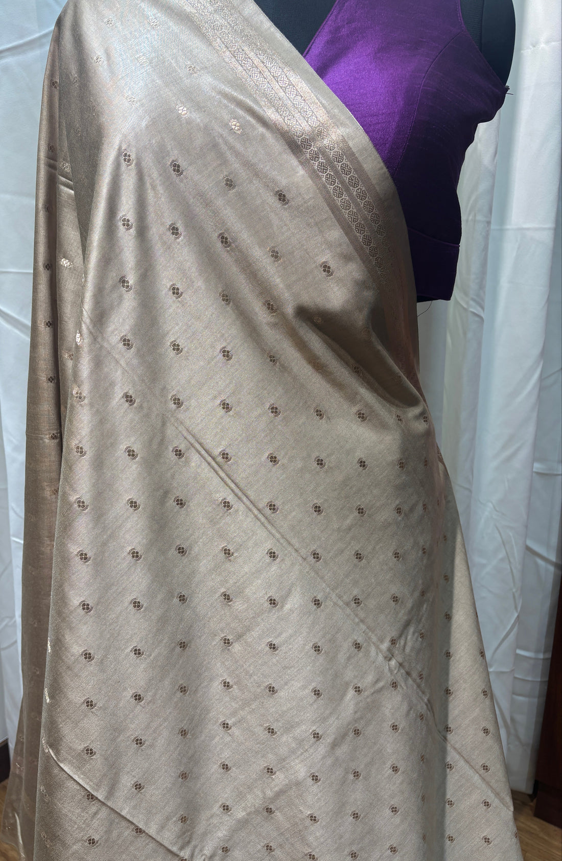 Mannequin wearing a long, light-colored dress with a pattern on a wooden floor.