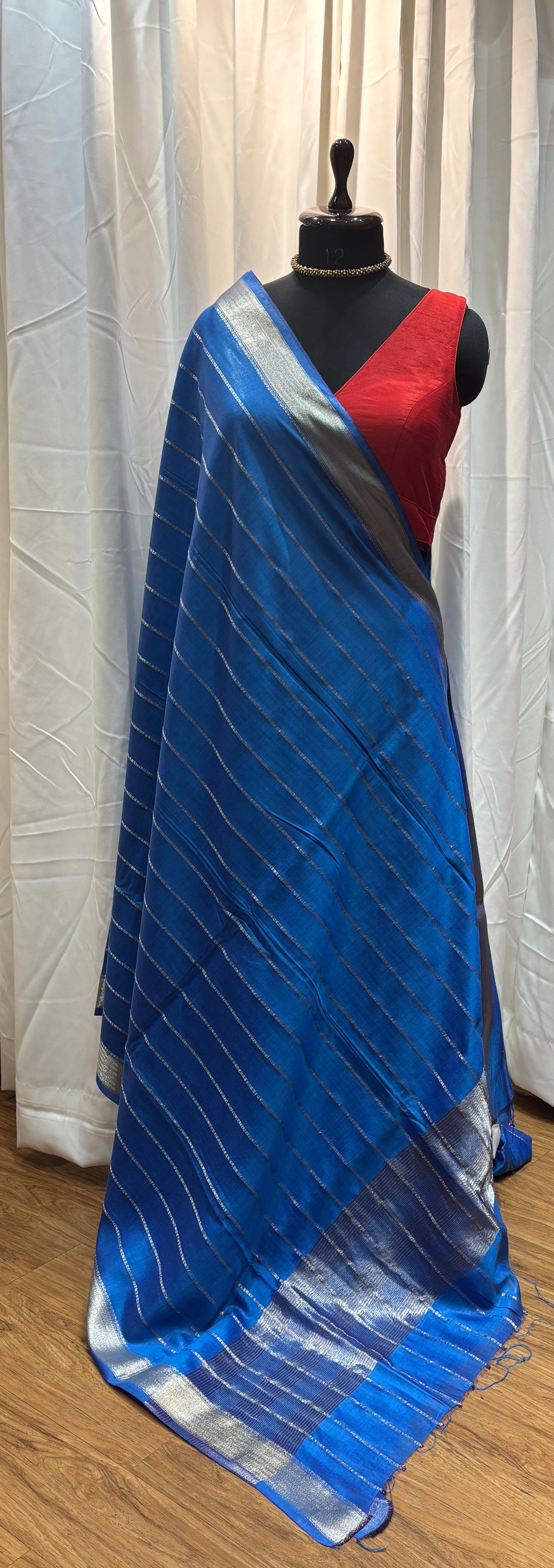 Blue inflatable raft on a wooden floor with colorful fabric in the background