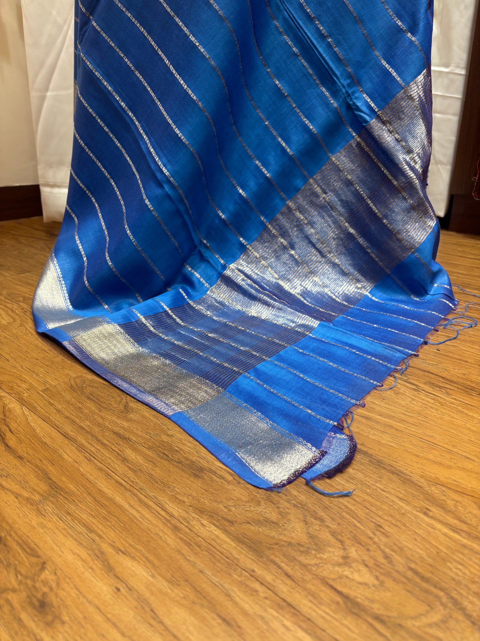 Blue fabric with silver stripes on a wooden surface
