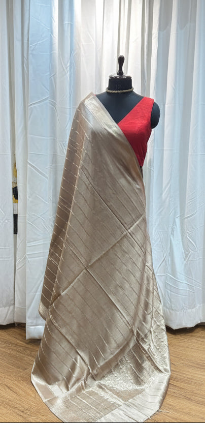 Mannequin with a beige dress on a wooden floor next to colorful fabric rolls.