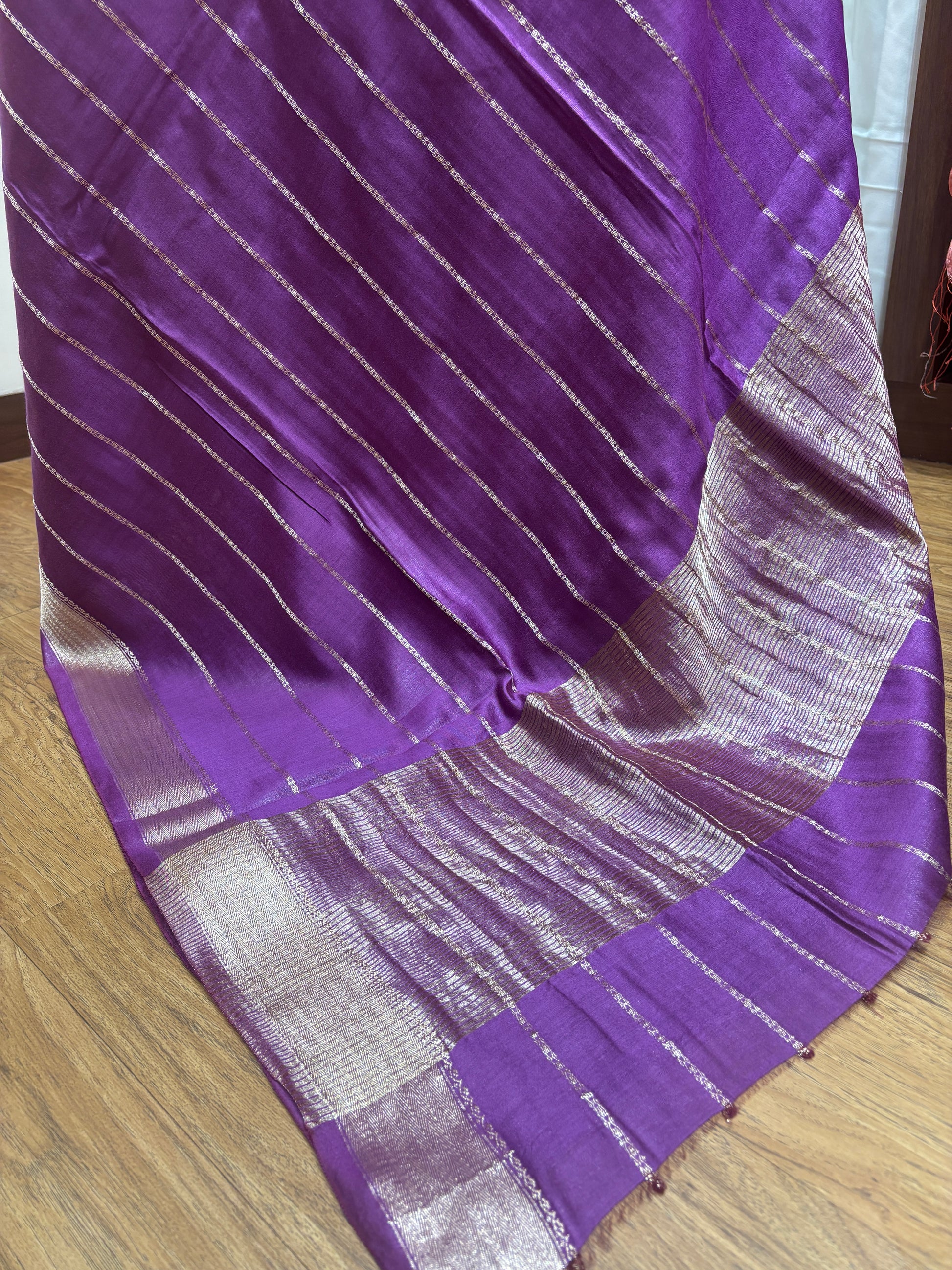 Purple fabric with silver stripes on a wooden surface